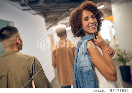 Joyful office worker posing for the camera in the corridor 97478636