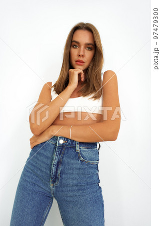 Young model woman in white underwear and jeans posing on studio background Young model woman in white underwear and jeans posing on studio background 97479300