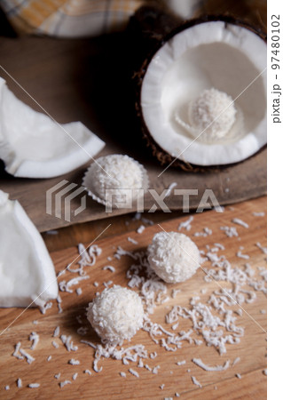 Close up of coconut with white pulp, coconut chip and white candies on wooden background.. 97480102