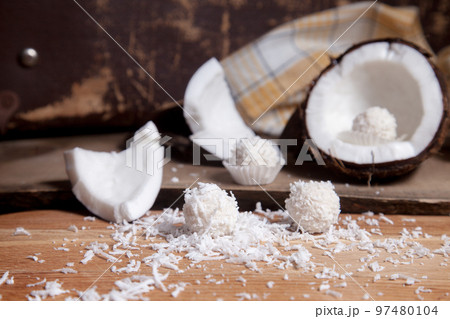 Close up of coconut with white pulp, coconut chip and white candies on wooden background.. Close up of coconut with white pulp, coconut chip and white candies on wooden background.. 97480104