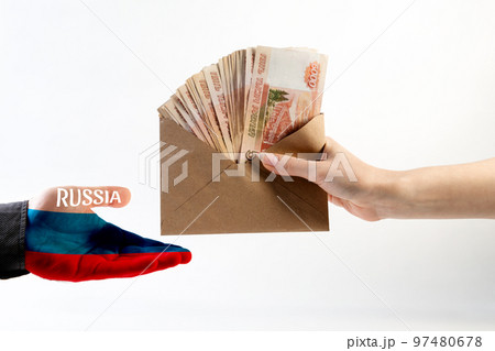 Illegal salary. A woman's hand gives an envelope of money to a man's hand in a shirt, with the palm painted in the flag of Russia. White background. The concept of the world anti-corruption day Illegal salary. A woman's hand gives an envelope of money to a man's hand in a shirt, with the palm painted in the flag of Russia. White background. The concept of the world anti-corruption day 97480678