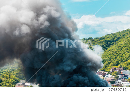 Fire in the village. Closeup of clouds of black smoke. The concept of an emergency, disaster and insurance Fire in the village. Closeup of clouds of black smoke. The concept of an emergency, disaster and insurance 97480712