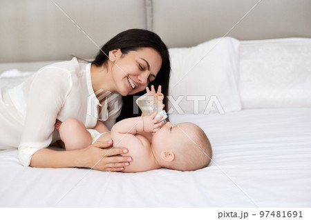 happy mother feeding her newborn baby on the bed happy mother feeding her newborn baby on the bed 97481691