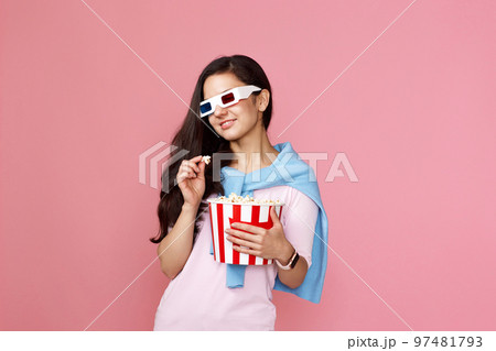 woman watching movie film, holding bucket of popcorn woman watching movie film, holding bucket of popcorn 97481793