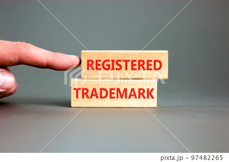Registered trademark symbol. Concept word Registered trademark on wooden blocks. Beautiful grey table grey background. Businessman hand. Business and registered trademark concept. Copy space. 97482265