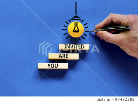 You are invited symbol. Concept words You are invited on wooden blocks. Businessman hand. Light bulb icon. Beautiful blue table blue background. Business and you are invited concept. Copy space. 97482288