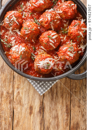Italian meatballs with parmesan in spicy tomato sauce close-up in a frying pan. Vertical top view 97482907