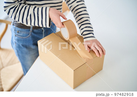 段ボールに荷物を詰める若い女性 97482918