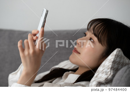 ソファに寝転んでスマホを使う女性 ソファに寝転んでスマホを使う女性 97484400