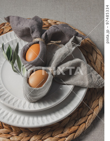 Festive Easter table setting. Funny Easter bunny made of eggs and linen napkin on plate. Gray background 97485334