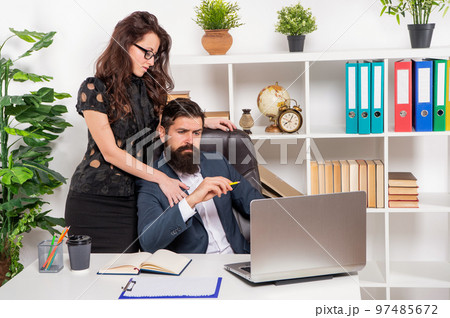 Developing flirtatious relationship. Woman touching man at work. Workplace relationship 97485672