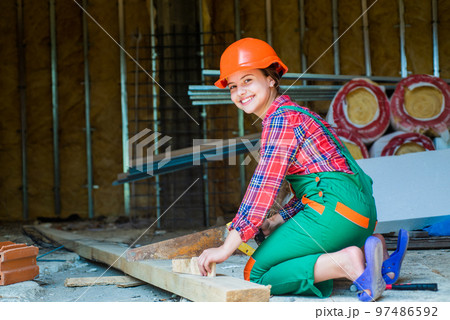kid sawing a plank in carpentry. working with wood in a garage. happy childhood. hardworking child sawing with hand wood saw. teenage girl with hand-saw. little girl working with wood kid sawing a plank in carpentry. working with wood in a garage. happy childhood. hardworking child sawing with hand wood saw. teenage girl with hand-saw. little girl working with wood 97486592