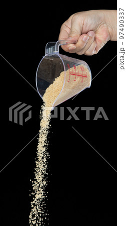 Brown Sugar fall, brown grain sugar pouring down abstract cloud fly from measuring cup. Beautiful complete seed sugarcane, food object design. Selective focus freeze shot Black background isolated 97490337