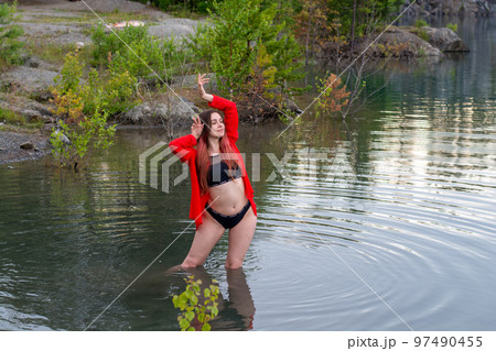 a girl in a black swimsuit and a red shirt in the lake 97490455