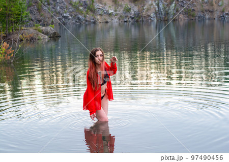 a girl in a black swimsuit and a red shirt in the lake 97490456