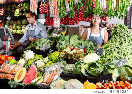 Portrait of welcoming female shop assistant and working male seller in vegetable shop 97492084