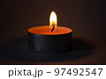 Candle on dark luxury night background. Black table, side view. Candles Burning at Night. Orange taper burning in focus, foreground. illustration design. 97492547