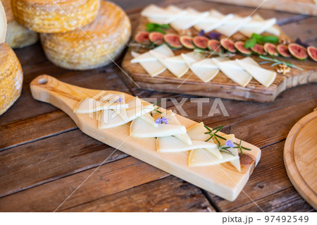 Delicious cheese slices served with rosemary sprouts and flowers on wooden cutting board 97492549