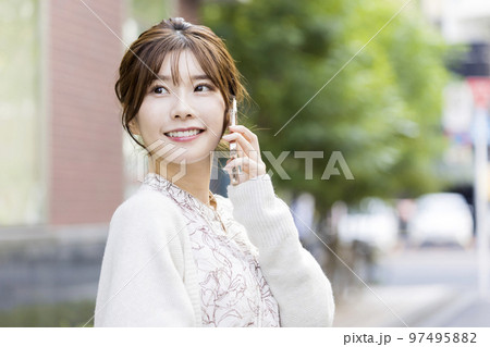 街中でスマートフォンで連絡をする女性 97495882