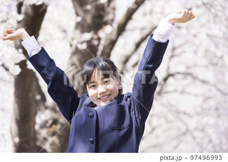 桜の前で万歳をする新中学生　小学校卒業　入学イメージ 97496993