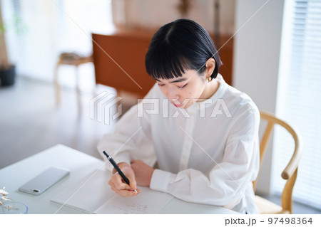 部屋でノートに書きものをする若い女性 部屋でノートに書きものをする若い女性 97498364