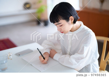 部屋でノートに書きものをする若い女性 部屋でノートに書きものをする若い女性 97498365