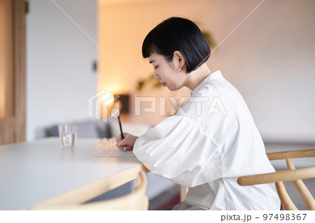 部屋でノートに書きものをする若い女性 部屋でノートに書きものをする若い女性 97498367