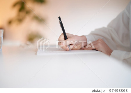 部屋でノートに書きものをする若い女性 97498368