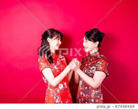 赤い背景に伝統的なチャイナドレスを着て微笑む若い娘と母のポートレート。 97498489