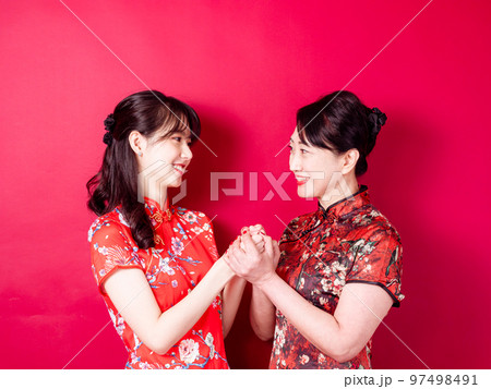 赤い背景に伝統的なチャイナドレスを着て微笑む若い娘と母のポートレート。 赤い背景に伝統的なチャイナドレスを着て微笑む若い娘と母のポートレート。 97498491