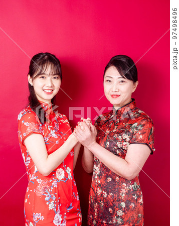 赤い背景に伝統的なチャイナドレスを着て微笑む若い娘と母のポートレート。 赤い背景に伝統的なチャイナドレスを着て微笑む若い娘と母のポートレート。 97498496