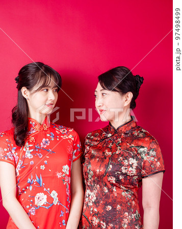 赤い背景に伝統的なチャイナドレスを着て微笑む若い娘と母のポートレート。 97498499