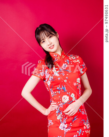 伝統的なチャイナ ドレスを着たアジアの若い女性の肖像画は、赤い背景