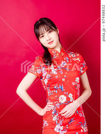 伝統的なチャイナ ドレスを着たアジアの若い女性の肖像画は、赤い背景
