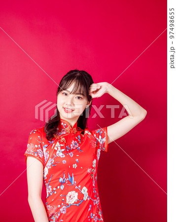 赤い背景に絶望的な頭痛に苦しむ伝統的なチャイナドレスを着た美しいアジア人女性。 97498655