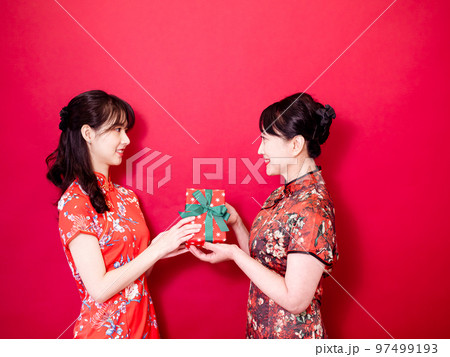 伝統的なチャイナ ドレスを身に着けている若い娘は、お母さんを祝福し、ギフト 97499193