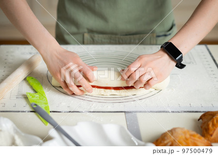 Woman hands with electronic bracelet cooking homemade pastry on silicone baking mat with markers 97500479