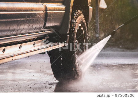 Washing offroader car at a self-service car wash with a high-pressure water jet after off-road driving 97500506