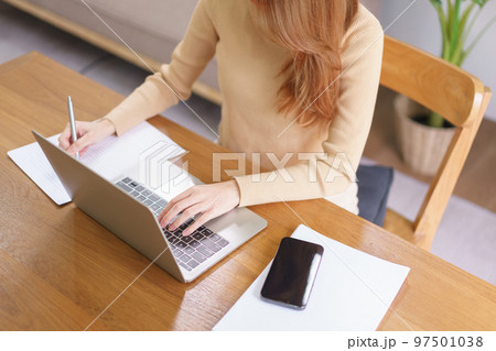 Business at home concept, Young Asian woman is reading data on laptop and taking notes on notebook Business at home concept, Young Asian woman is reading data on laptop and taking notes on notebook 97501038