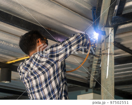 A welder is working on a steel frame. At the construction site. 97502551