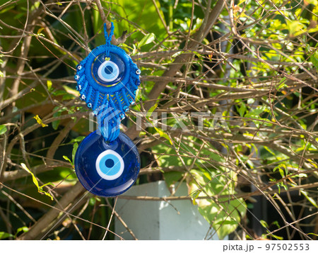 Close up of evil eye charms hang from a tree. 97502553