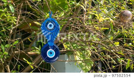 Close up of evil eye charms hang from a tree. Close up of evil eye charms hang from a tree. 97502554