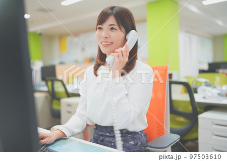 オフィスで電話応対をする女性	 97503610