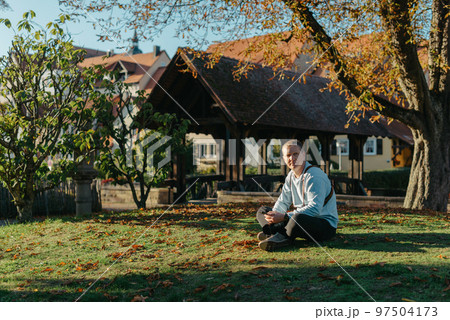 Professional Photographer Taking Picture Of Beautiful Autumn Park. Man Professional Photographer Sit With Camera And With Smartphone In Autumn Park. Retouched, Vibrant Colors, Brownish Tones. 97504173