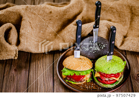Top down view of set of three mini color homemade burgers with marble beef with knife rustic table Top down view of set of three mini color homemade burgers with marble beef with knife rustic table 97507429