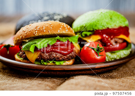 Closeup of set of three color homemade burgers with marble beef on rustic table. selective focus  97507456