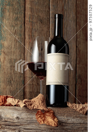 Bottle and glass of red wine on an old wooden table. 97507529