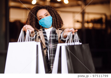 Young woman in protective medical mask with shopping bags 'near mall. Beautiful woman after shopping. 97511799