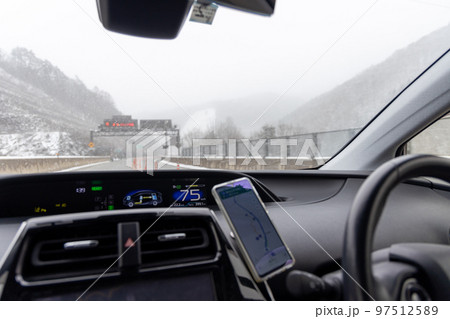 冬に雪が積もり始めた高速道路を走行する乗用車の運転席からの眺め 冬に雪が積もり始めた高速道路を走行する乗用車の運転席からの眺め 97512589