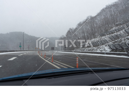 うっすらと雪の積もった高速道路を走る乗用自動車からの風景 97513033